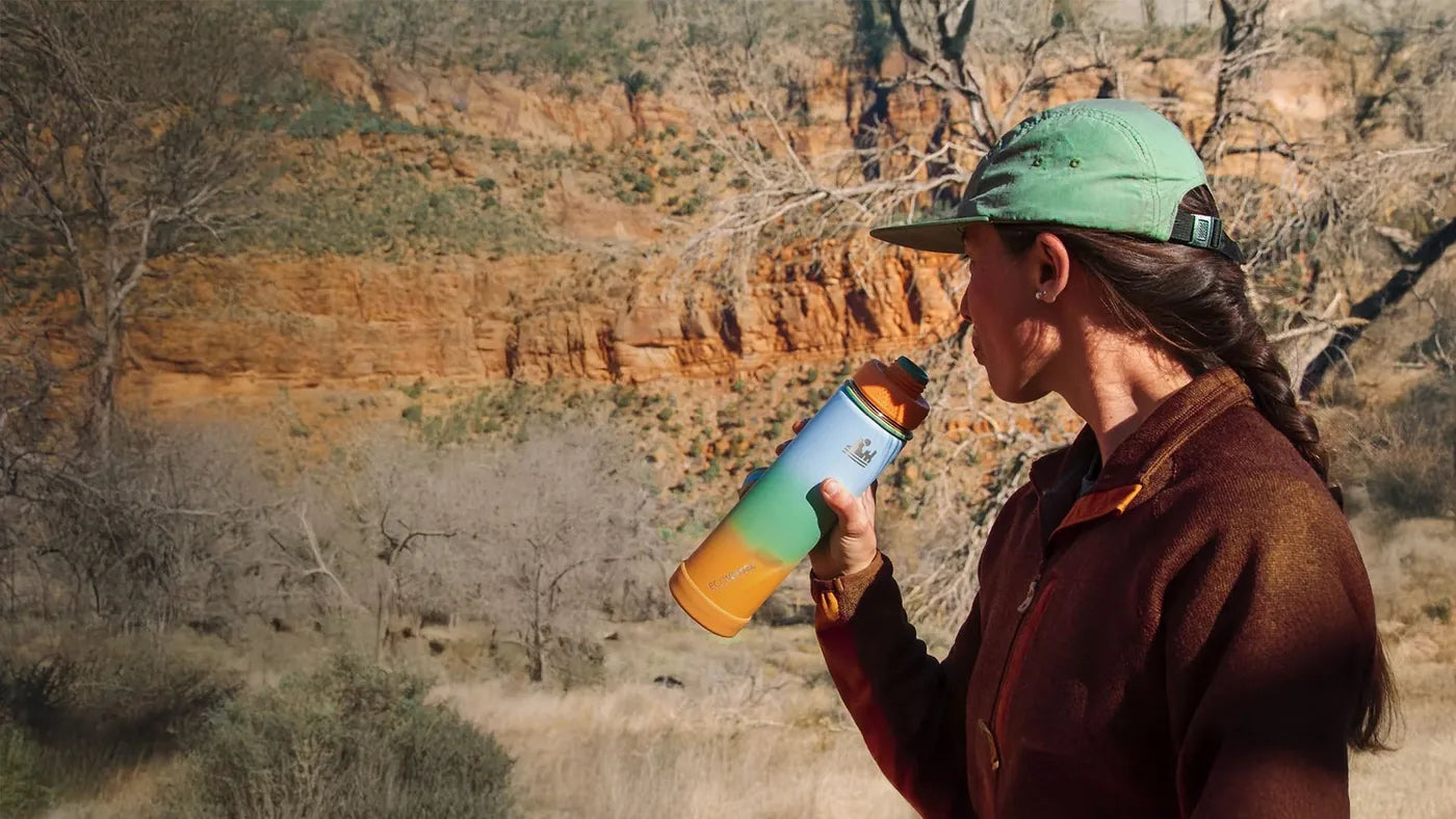 A hiker drinking from an EcoVessel insulated bottle