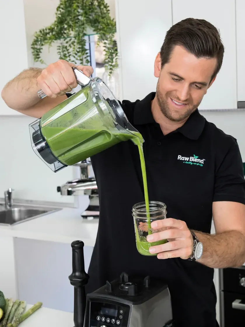 Tommy from Raw Blend pouring a fresh green smoothie into a glass jar
