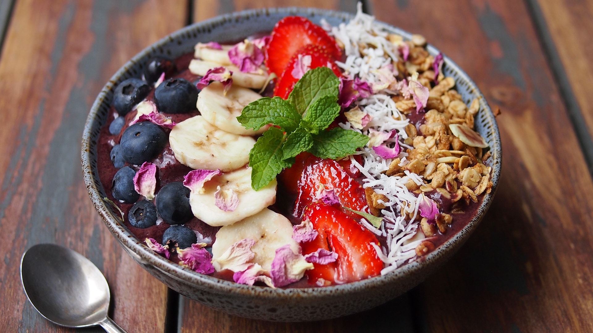 Picture of an acai bowl, topped with strawberries, bananas and blueberries